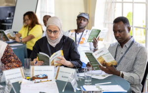 A group of people sitting around tables, all reading their SEADS Handbooks